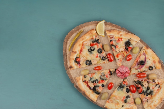 Delicious hot pizza with olives and tomatoes on blue surface. 