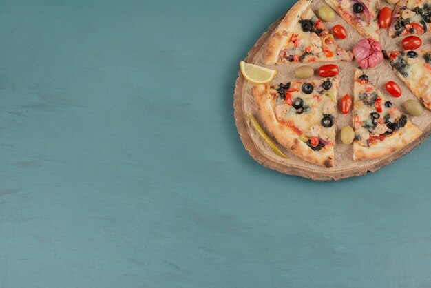 青い表面にオリーブとトマトが入ったおいしいホットピザ。