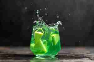 Free photo delicious juice in a glass with apple limes on dark background