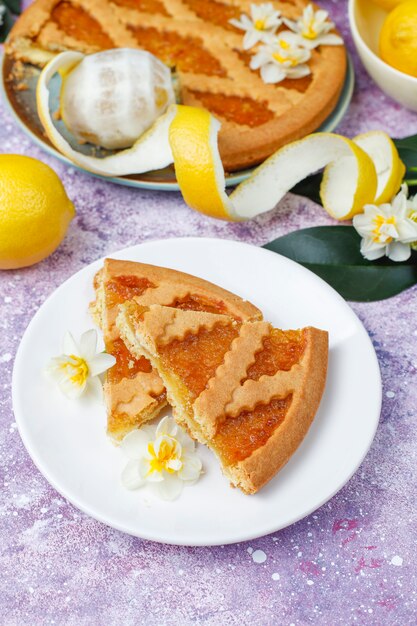 Delicious lemon pie slices with fresh lemons and a cup of tea ,top view