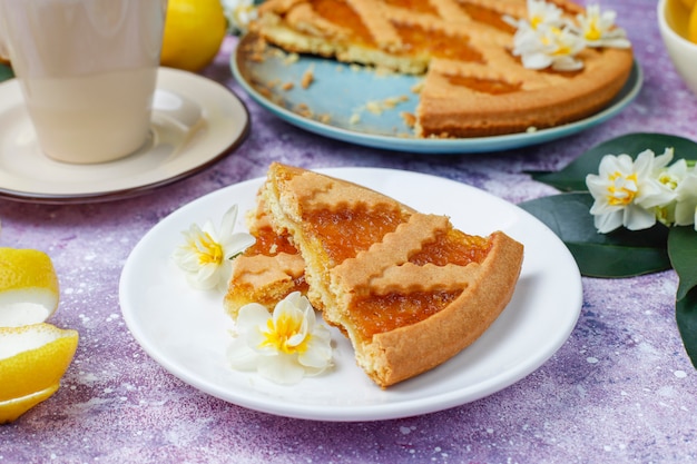 Вкусные ломтики лимонного пирога со свежими лимонами и чашкой чая, вид сверху