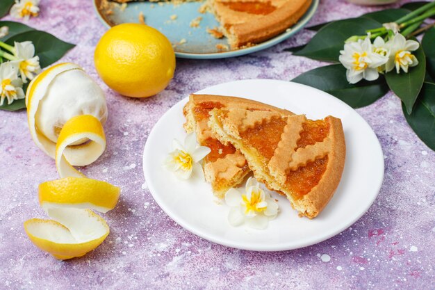 Delicious lemon pie slices with fresh lemons and a cup of tea ,top view