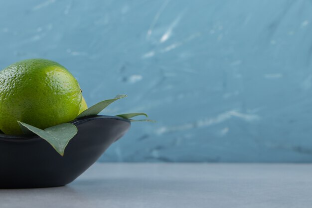 Delicious lime fruits in black bowl. 