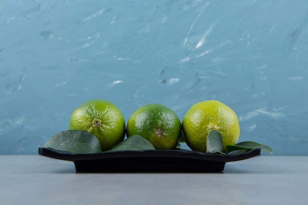 Delicious lime fruits on black plate. 