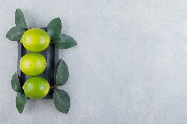 Delicious lime fruits with leaves on black plate