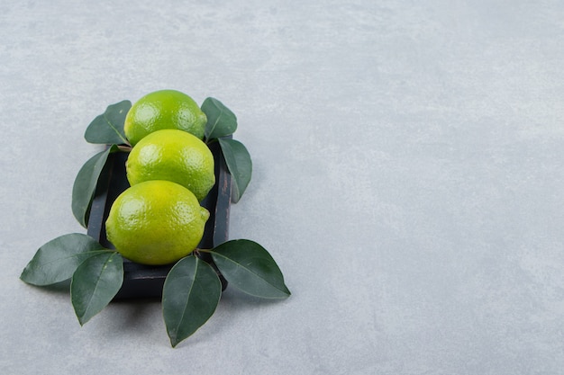 Delicious lime fruits with leaves on black plate