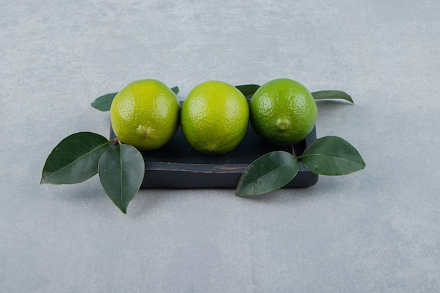 Delicious lime fruits with leaves on black plate