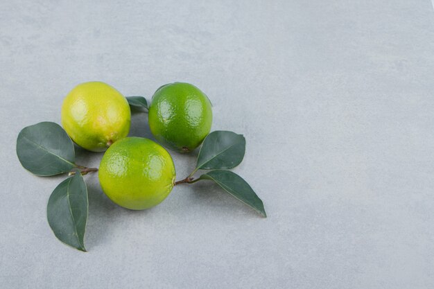 Delicious lime fruits with leaves on stone table. 