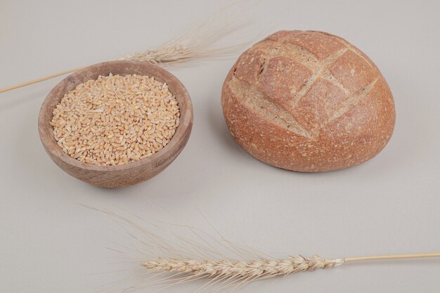 Delicious loaf of bread with oat grain on white surface