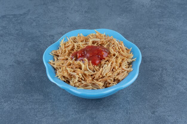 Delicious macaroni with ketchup in blue bowl. 