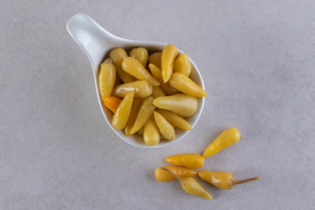 Delicious marinated pickled peppers placed on stone table.