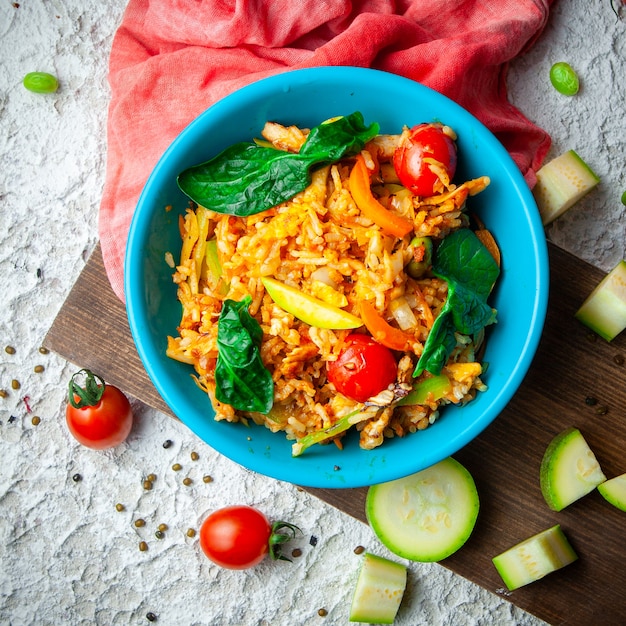 Delicious meal in a blue plate on a wood, red cloth and white textured background. top view.