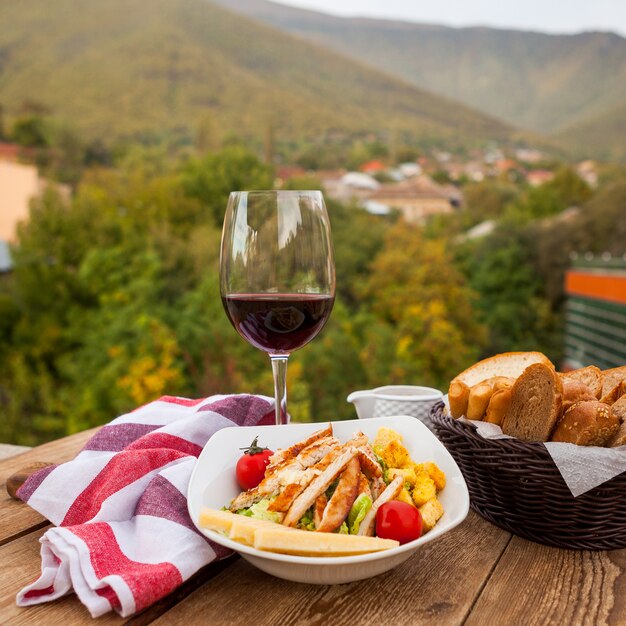 Delicious meal in a bowl with wine and bread side view with a village on background