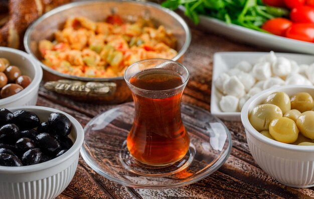 Delicious meal in a plate with a cup of tea, salad, pickles top view on a wooden surface