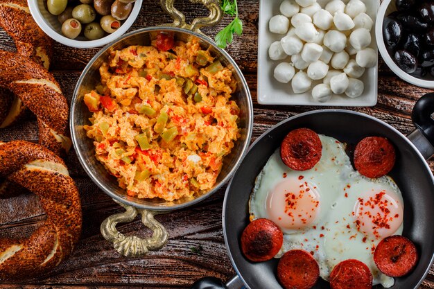 Delicious meals in a pot and pan with turkish bagel, pickles top view on a wooden surface