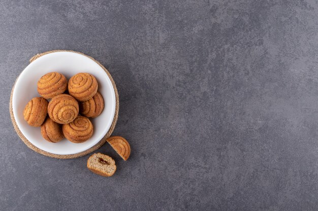 Delicious mini cinnamon cakes placed on stone table.