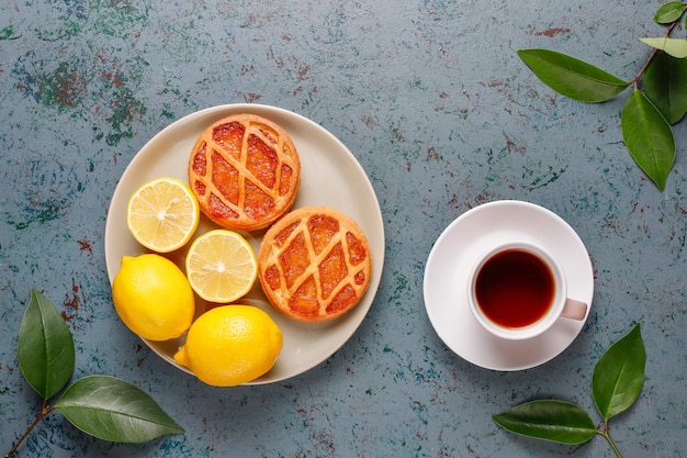 Delicious mini lemon pies with fresh lemons, top view