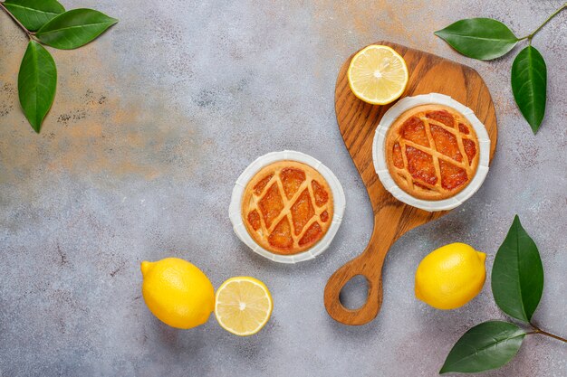 Delicious mini lemon pies with fresh lemons, top view