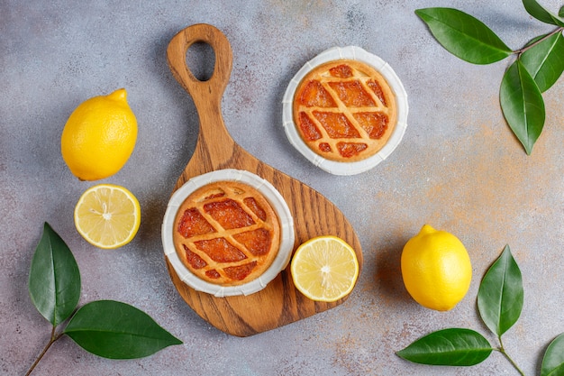 Delicious mini lemon pies with fresh lemons, top view