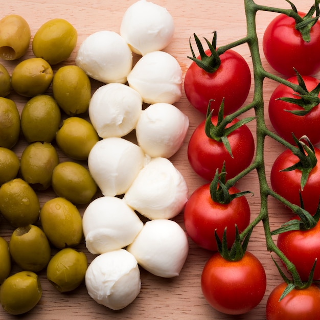 Delicious mozzarella cheese; fresh red tomatoes and wet olives on wooden table