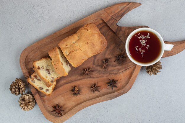 Delicious muffin with raisin and cup of tea on wooden board