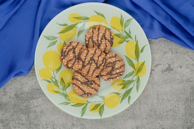 Foto gratuita deliziosi biscotti multicereali con glassa al cioccolato su piatto in ceramica.