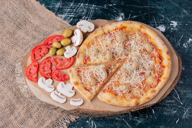 Deliziosa pizza ai funghi con formaggio e verdure fresche su marmo.