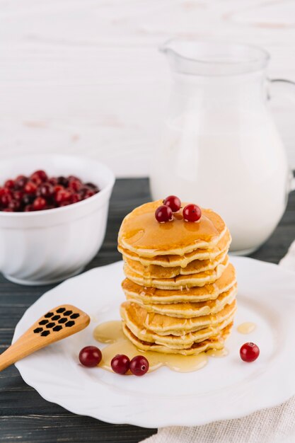 Delicious pancakes with honey and red currant berries on white plate