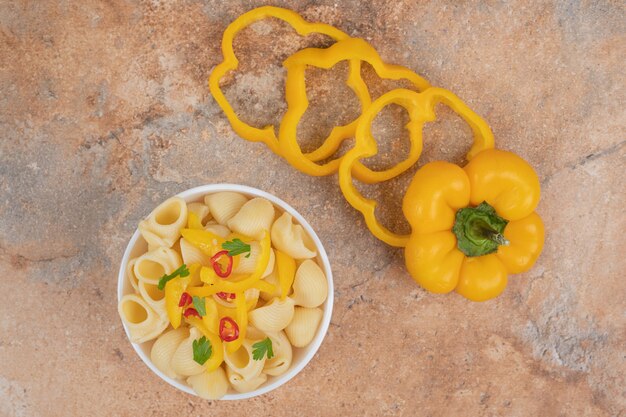 Delicious pasta and pepper slices on orange background