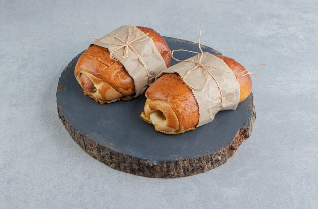 Delicious pastries with sausages on wooden piece.