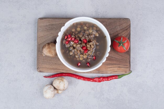 Delicious peas soup with mushrooms and tomato on wooden board . 