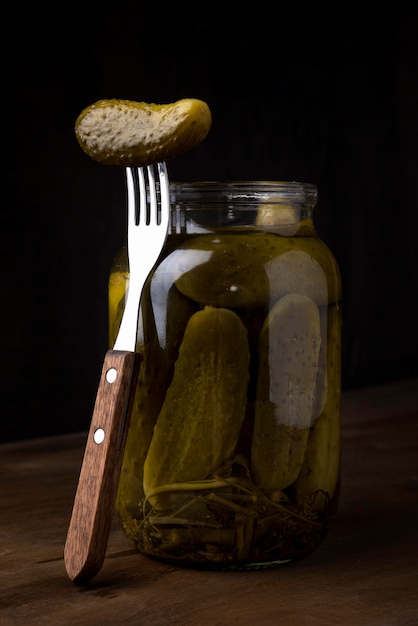 Delicious pickles in jar with fork