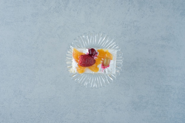 Delicious piece of cake on glass plate on marble background