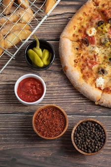 Вкусная пицца с оливками и жареным картофелем на деревянном столе.