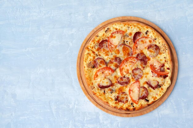 Delicious pizza with sausages on gray background