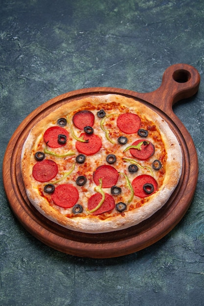 Delicious pizza on wooden cutting board on dark blue surface with free space in vertical view