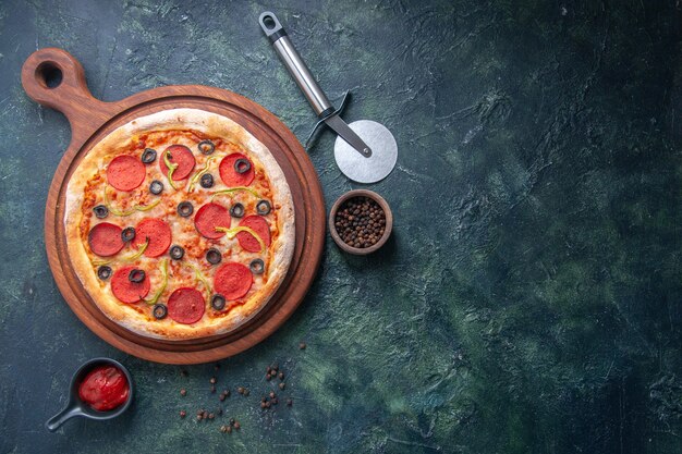고립 된 어두운 표면의 오른쪽에 나무 커팅 보드와 고추 케첩에 맛있는 피자