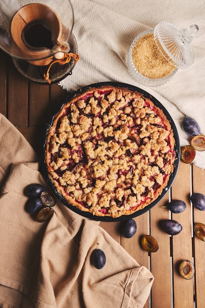 Deliziosa torta di prugne con caffè chemex e ingredienti con tessuto su un tavolo in legno con tessuto