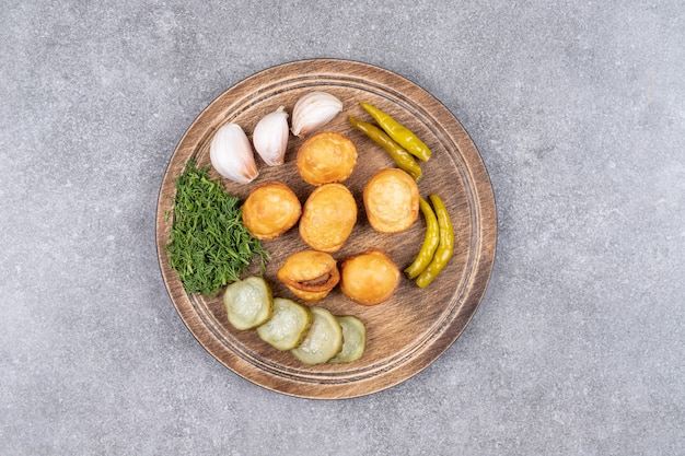Вкусные картофельные крокеты с овощными консервами на деревянной доске.