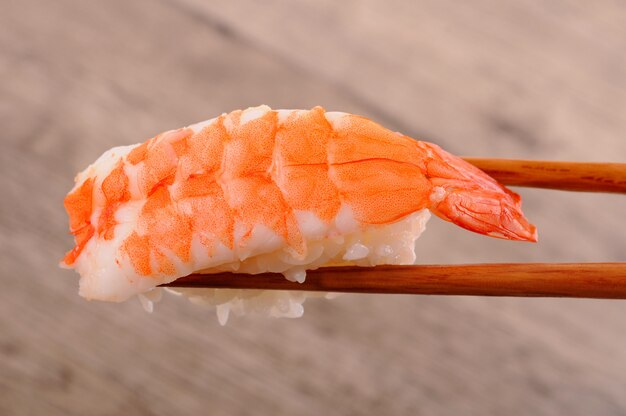 Delicious prawn sushi held by chopsticks