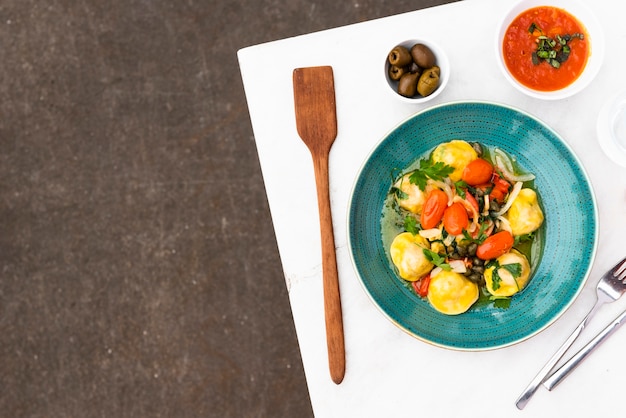 Бесплатное фото Вкусная паста равиоли с томатным соусом и оливками на столе