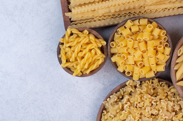 Delicious raw macaroni and vermicelli on wooden bowls