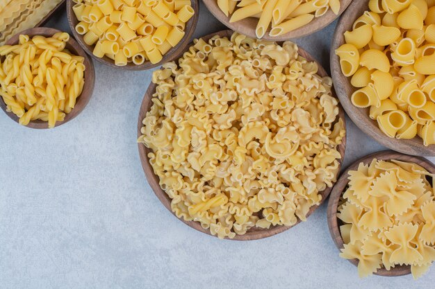 Delicious raw macaroni and vermicelli on wooden bowls