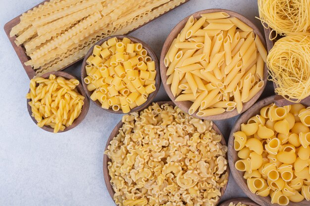 Delicious raw pasta and macaroni on wooden bowls . 