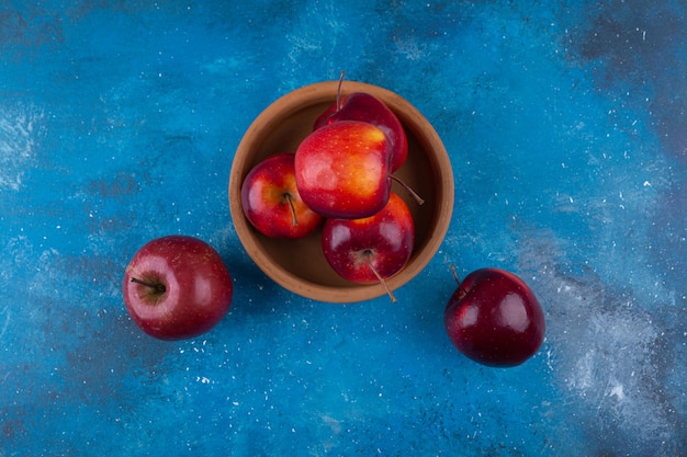 Delicious red shiny apples placed on blue table.