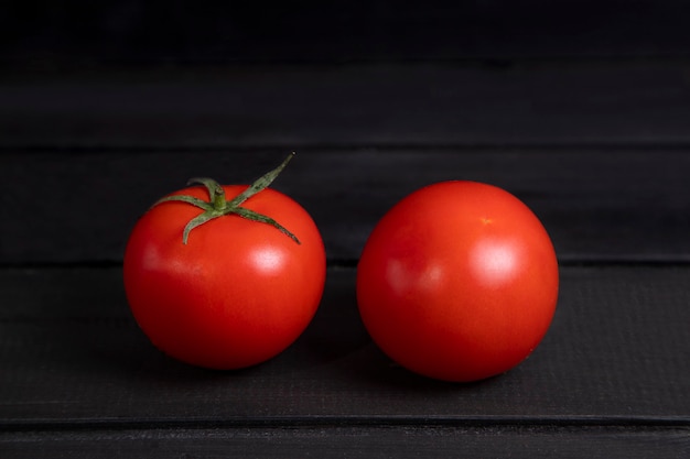 Free photo delicious red tomatoes placed on dark wooden surface. high quality photo