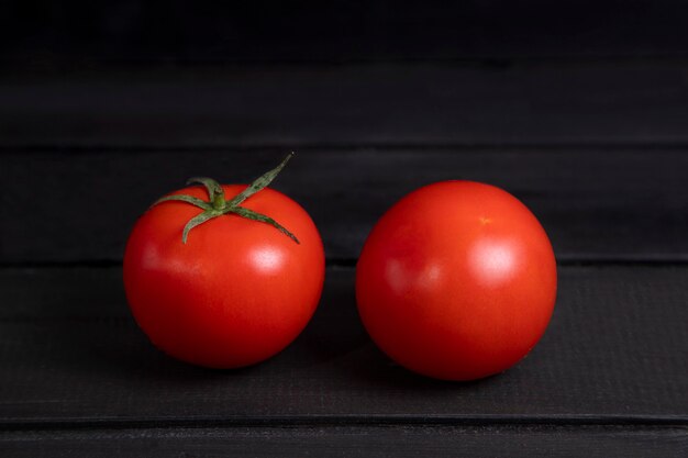暗い木の表面に置かれたおいしい赤いトマト。高品質の写真