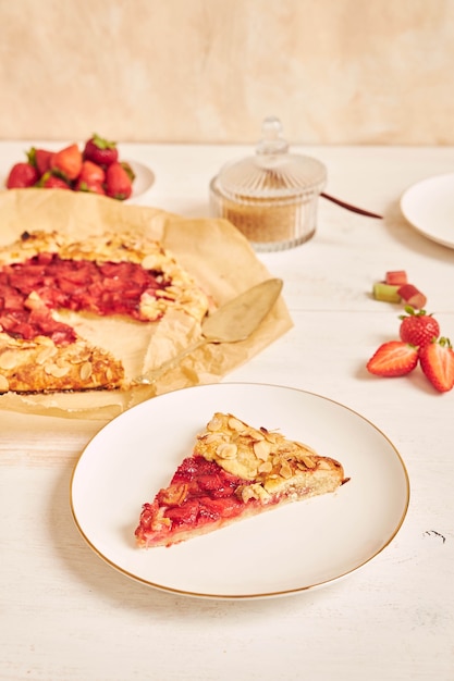 Delicious rhubarb strawberries gallate cake with ingredients on a white table