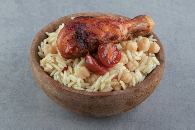 Free photo delicious rice with chickpeas and chicken chicken leg in wooden bowl.