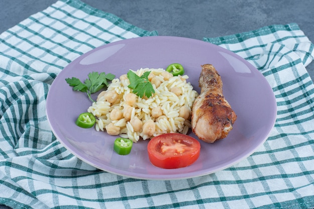 Foto gratuita delizioso riso con ceci e coscia su piatto viola.